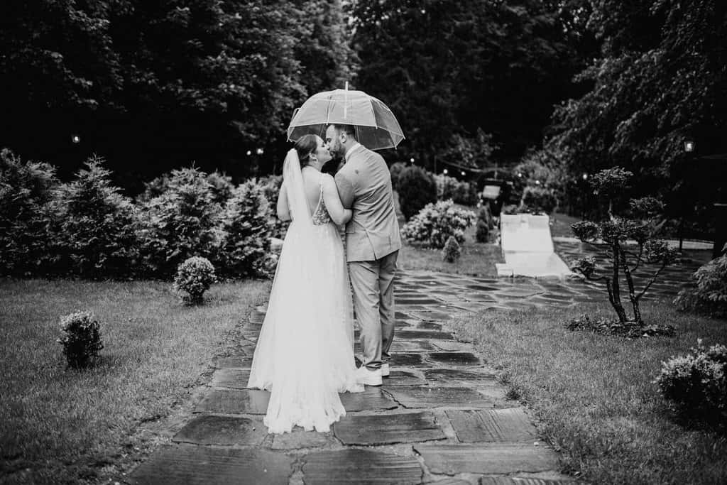 Ein Mann und eine Frau laufen unter einem Regenschirm und Küssen sich