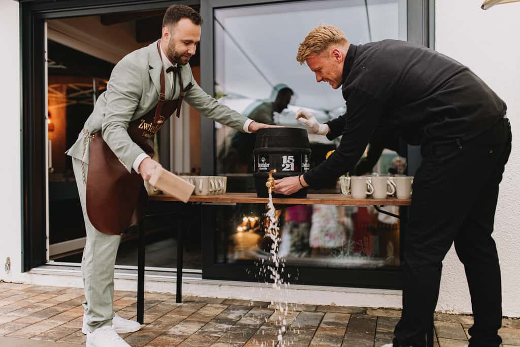 Ein Mann hält einen Hammer an die Hand eines anderen Mannes