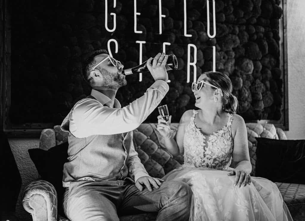 Ein Mann und eine Frau sitzen auf einer Couch und trinken aus einer Flasche