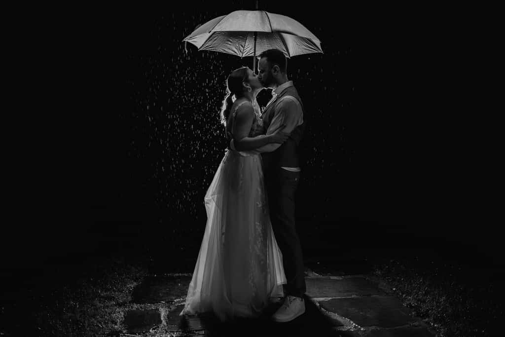 Ein Mann und eine Frau küssen sich unter einem Regenschirm