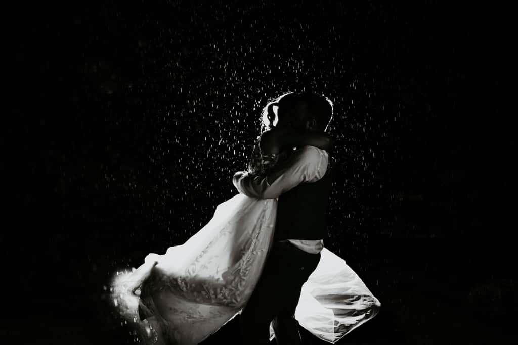 Eine Frau und ihr Mann im Hochzeitsdress Tanzen im Dunklem bei Regen