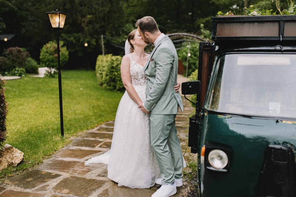 Ein Mann und eine Frau küssen sich vor einem Auto